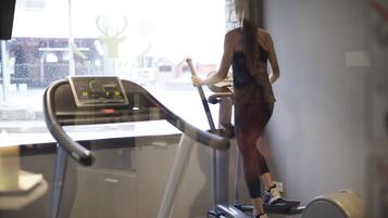 A person using a treadmill in a gym with a window view.