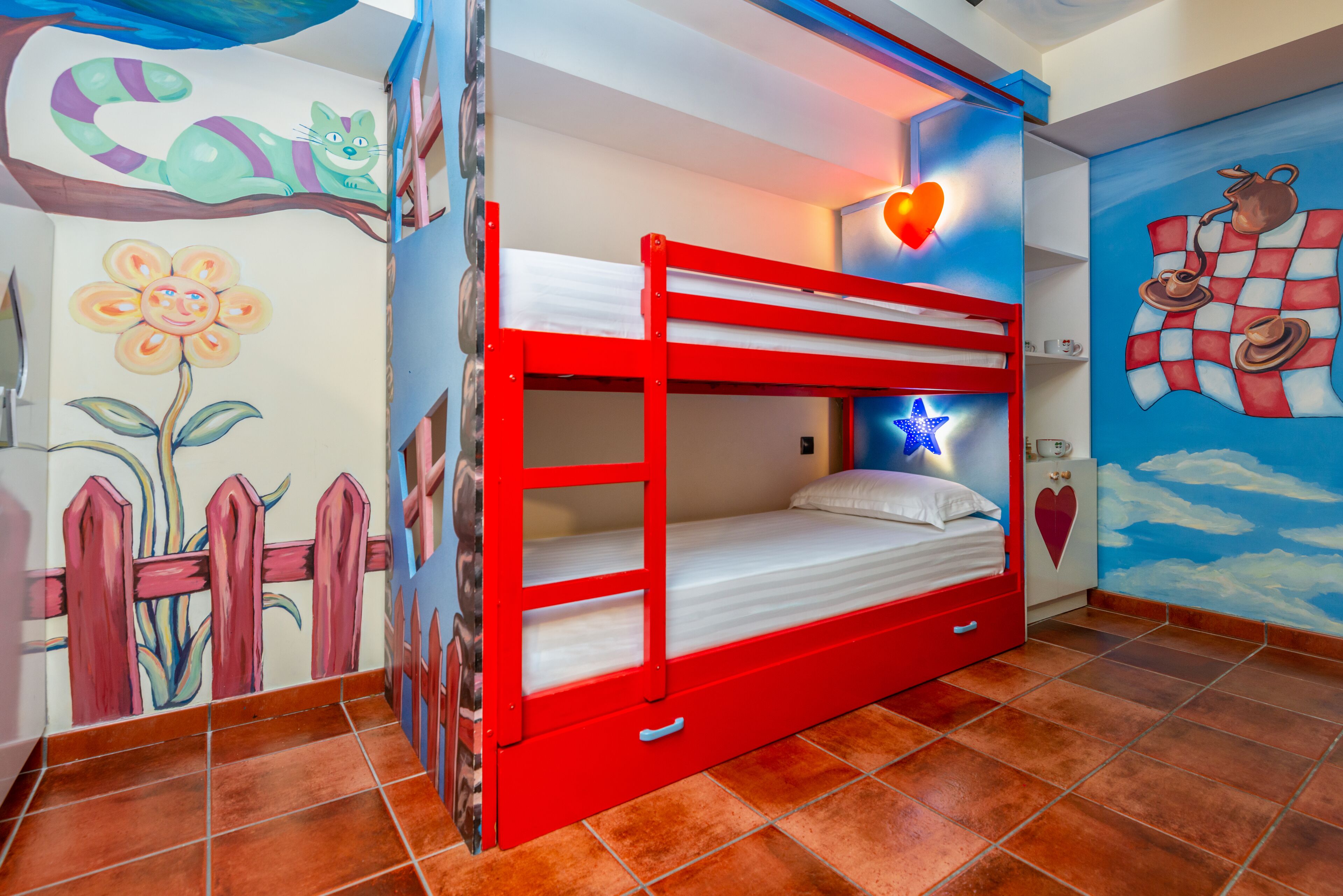 A bunk bed room with a mural of a cat, a flower, and a checkered pattern.