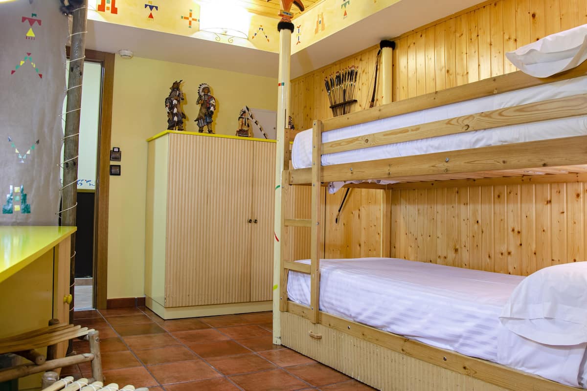 Habitación con literas, paredes de madera y una pared de acento amarilla.