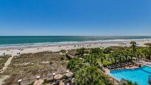 A beach resort with a swimming pool, beach chairs, and palm trees. - Carolina Dunes (Myrtle Beach)