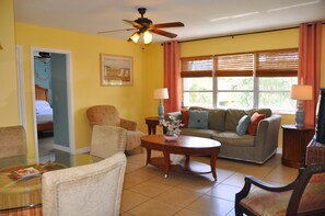 A living room with a ceiling fan, a sofa, a coffee table, and a dining table.