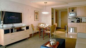 Une chambre d’hôtel moderne dotée d’un coin repas, d’une kitchenette et d’un téléviseur fixé au mur.