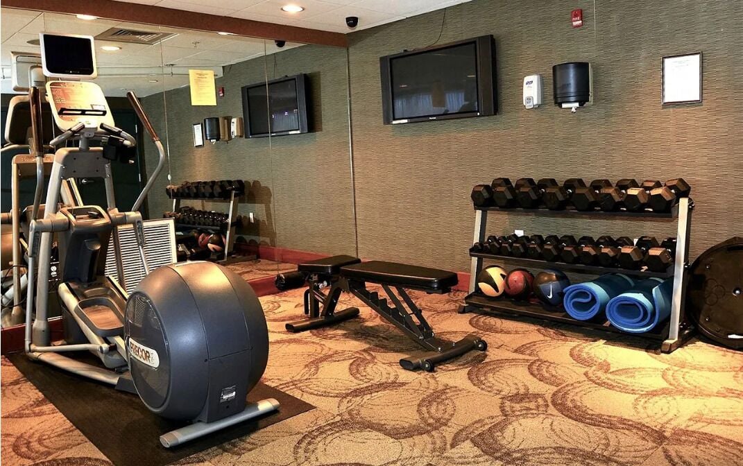 A gym with cardio equipment, dumbbells, and yoga mats.