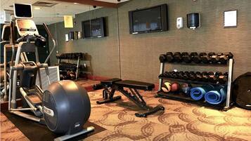 A gym with cardio equipment, dumbbells, and yoga mats.