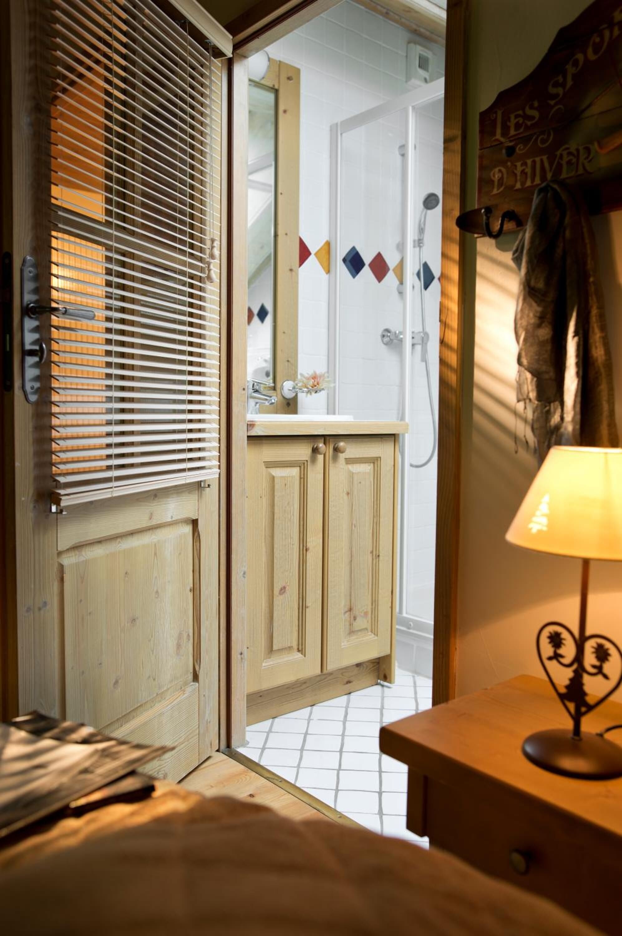 A wooden door leading to a bathroom with a shower, a towel rack, and a sign reading "LES SPORTS D'HIVER".