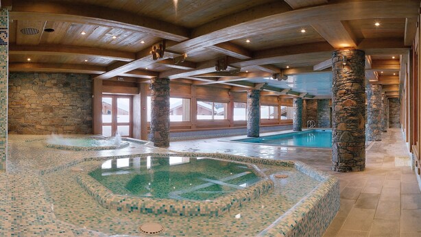 An indoor swimming pool with mosaic tile flooring and stone pillars. - CGH Résidences & Spas Le Hameau du Beaufortain (Villard-sur-Doron)