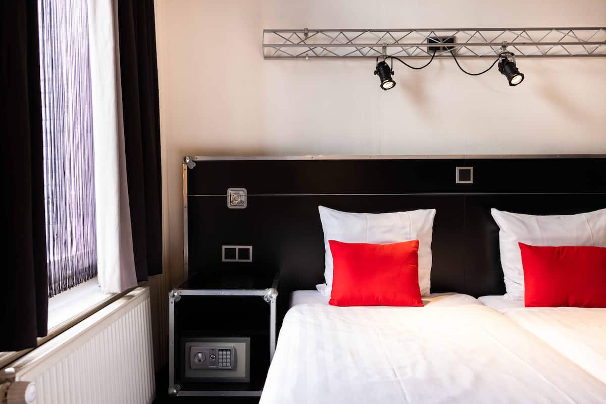 Ein Hotelzimmer mit einem Bett, einem Nachttisch, einem Heizkörper und einer Wandleuchte.