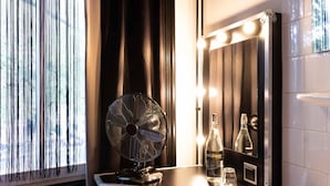 A vanity with a fan, bottles, and a mirror with lights. - Backstage Hotel Amsterdam (Amsterdam)