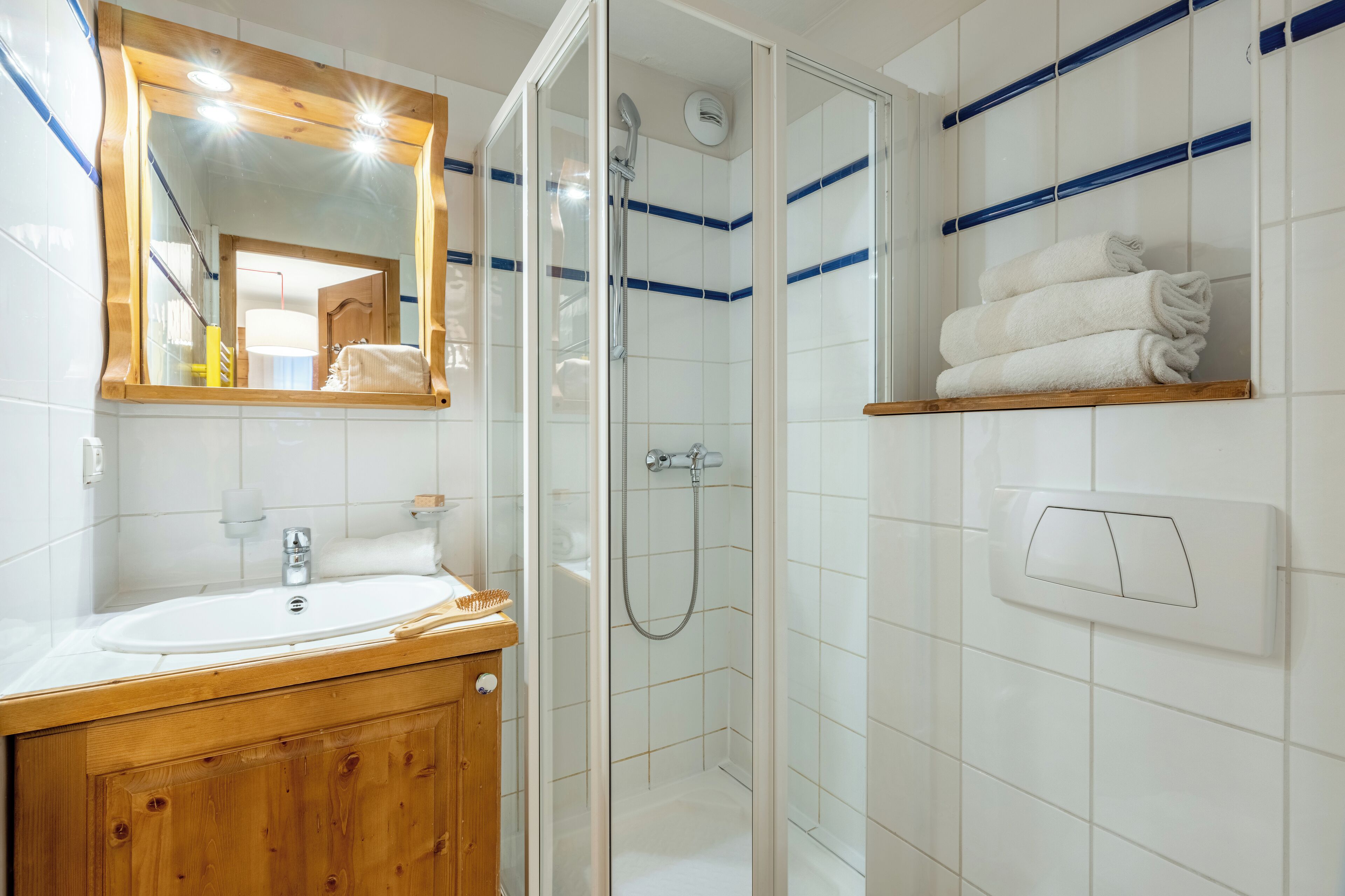 A bathroom with a wooden vanity, a glass-enclosed shower, and a towel rack.