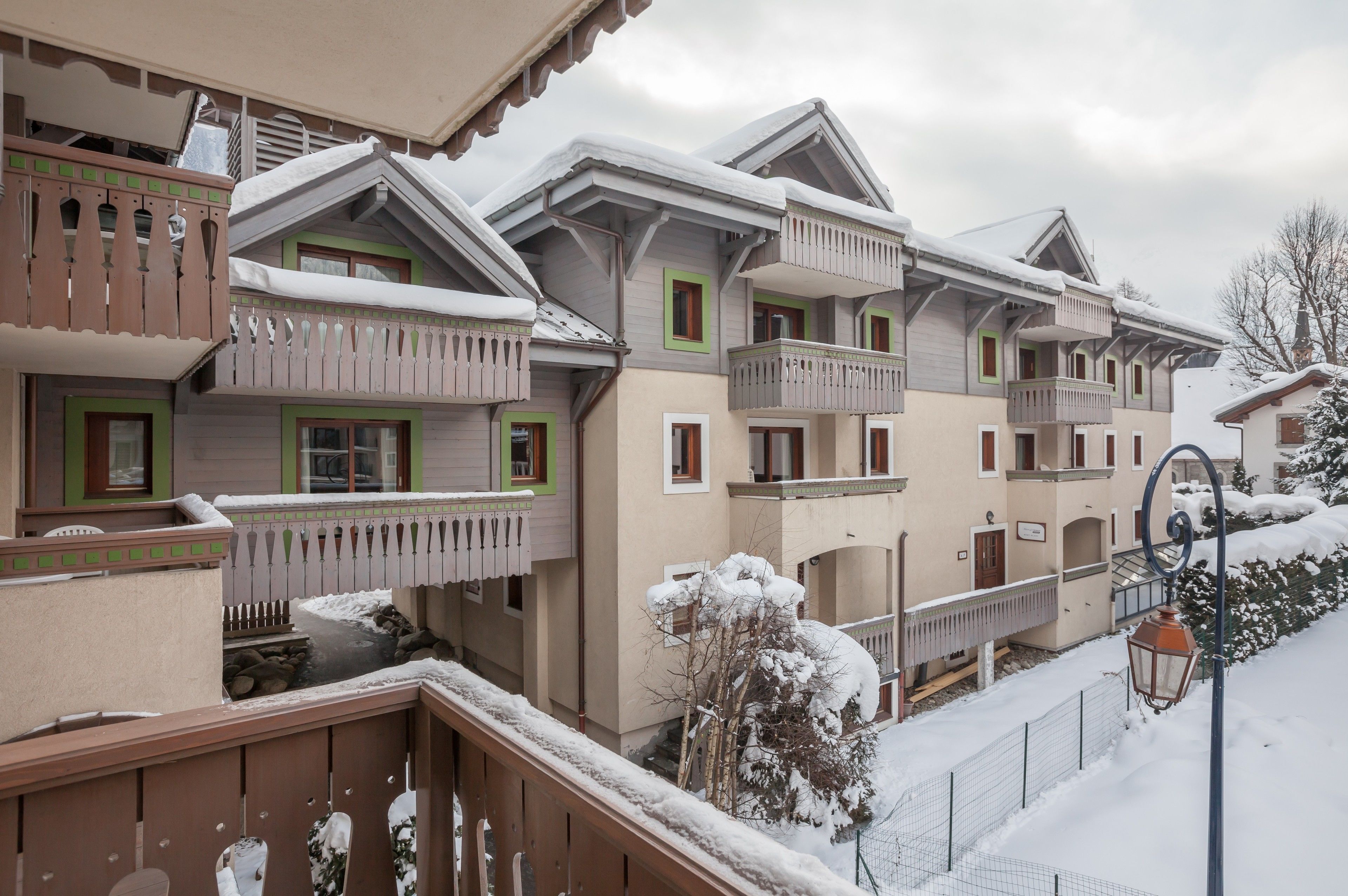 Una hilera de edificios de estilo chalet con balcones, barandillas de madera y techos cubiertos de nieve.