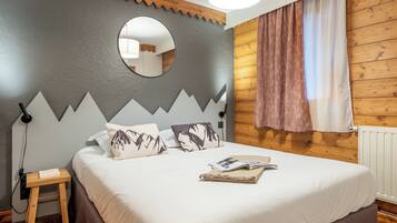 A bedroom with a bed, a nightstand, a mirror, and a window with curtains.
