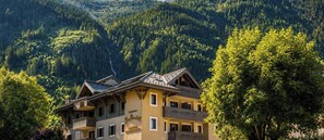 A multi-story building with balconies, surrounded by forested hills. - Résidence Pierre & Vacances Premium La Ginabelle (Chamonix-Mont-Blanc)
