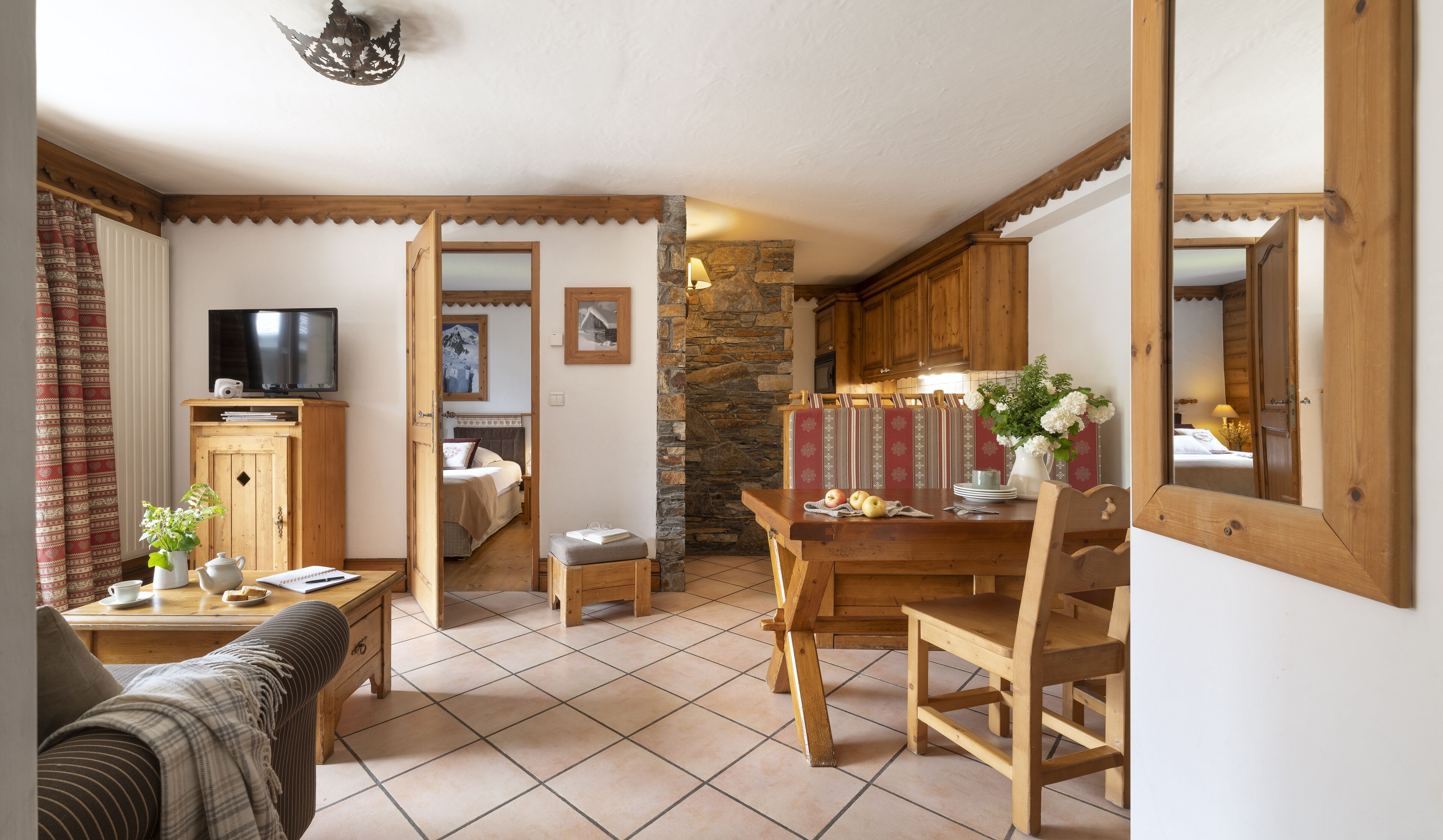 Una sala de estar acogedora con una mesa de comedor de madera, un sofá, un televisor y una cocina con una pared de piedra.