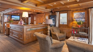 Un interior de madera con una mesa de recepción, asientos acolchados y un ventanal con vistas a la montaña.