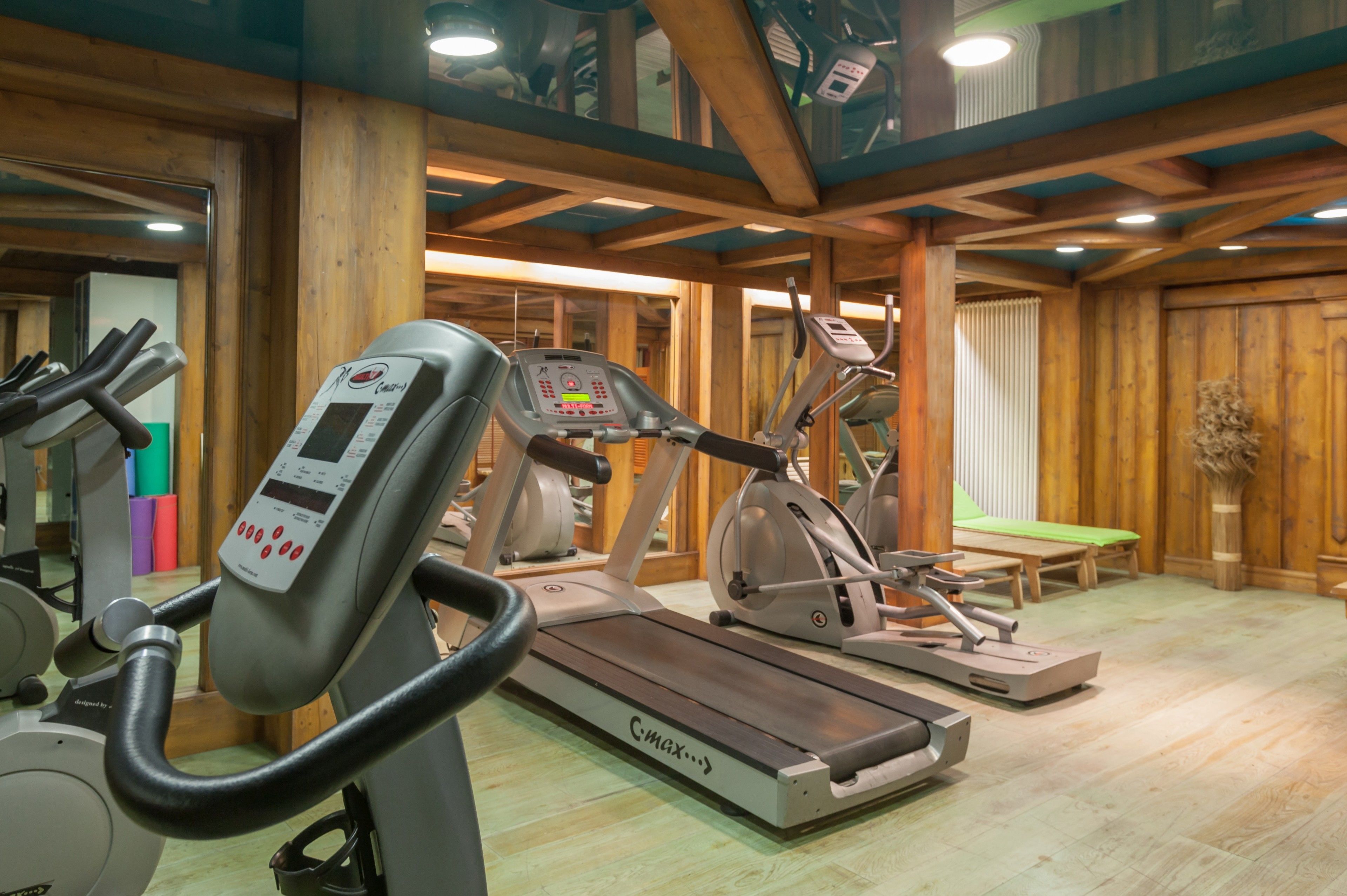 Ett gym med konditionsmaskiner, träväggar och en bänk.