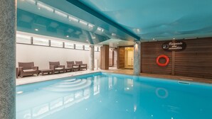 Una piscina interior con sillones de descanso y un flotador en la pared.