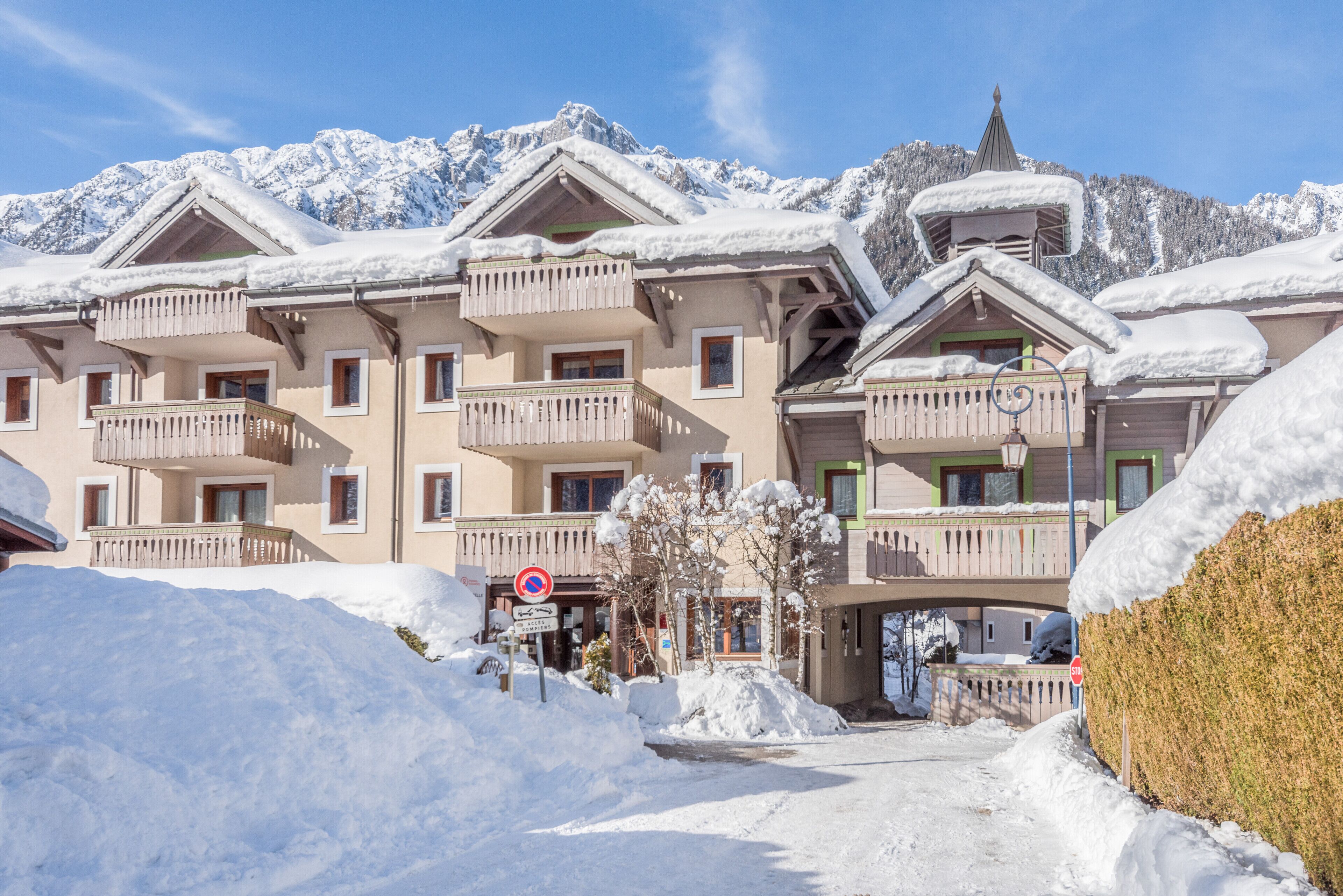 Un hotel con varios balcones, un cartel que indica prohibido estacionar y alrededores cubiertos de nieve.