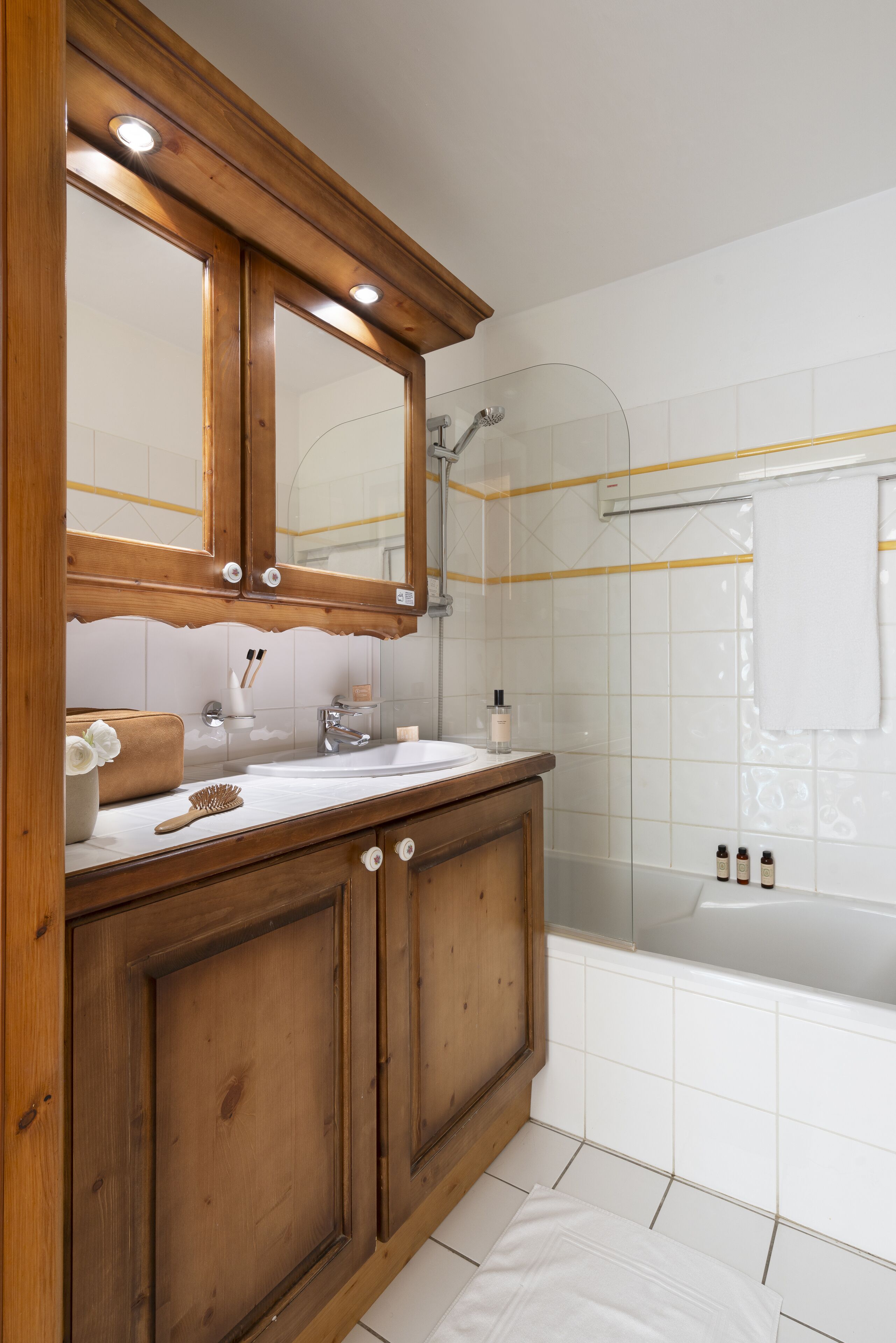 Une salle de bain avec un meuble-lavabo en bois, un grand miroir, une baignoire et une douche.