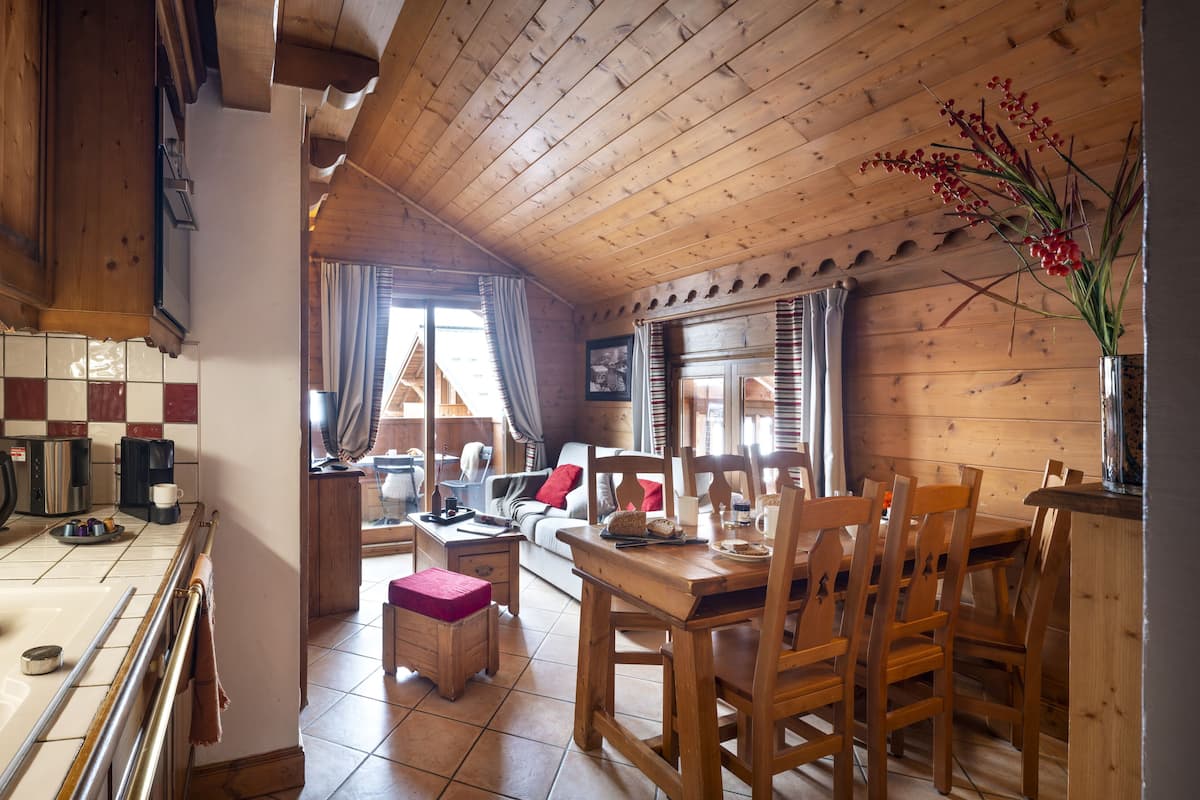 A cozy kitchen with wooden cabinets, a coffee machine, and a dining area with a table and chairs.