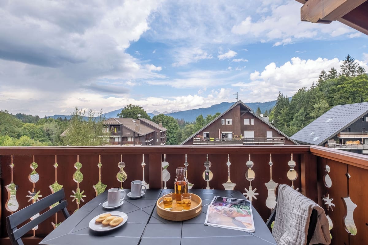 A balcony with a table set for two, a pitcher of beer, and a magazine.
