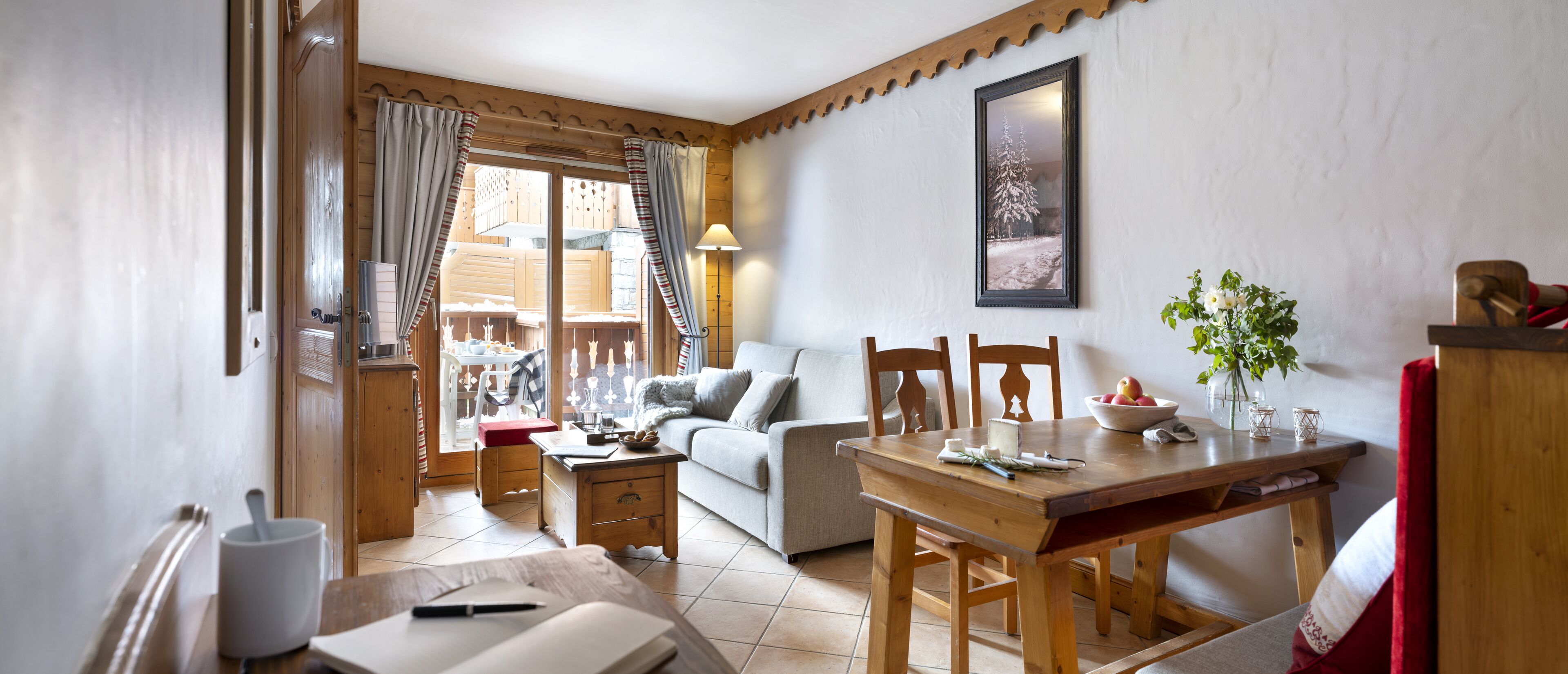A cozy living room with a wooden dining table, a sofa, and a wooden cabinet.