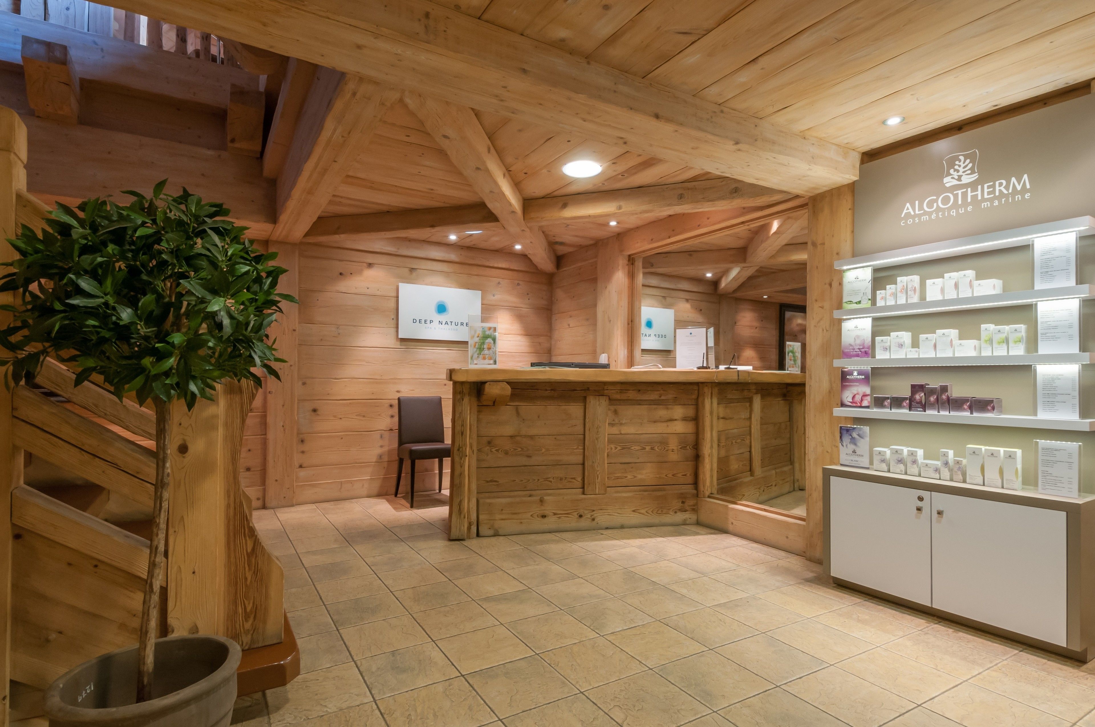 Un interior de madera con un mostrador de recepción, una planta en maceta y estantes mostrando productos.