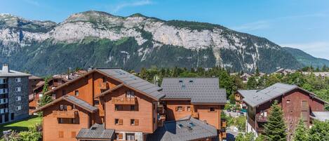 Un albergue de montaña con varias construcciones de madera, balcones y vistas a una cadena montañosa.
