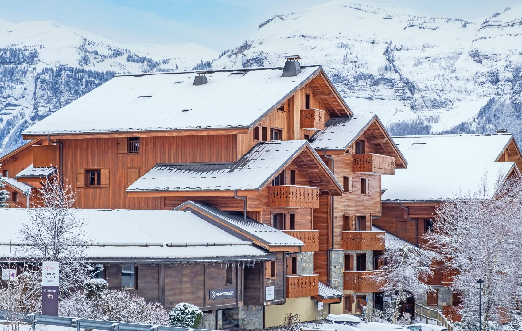 Un edificio de estilo chalé de madera con varios balcones, rodeado de montañas nevadas.