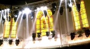 A theater interior with rows of seats and large stained glass windows. - Amsterdam Hostel Leidseplein (Amsterdam)