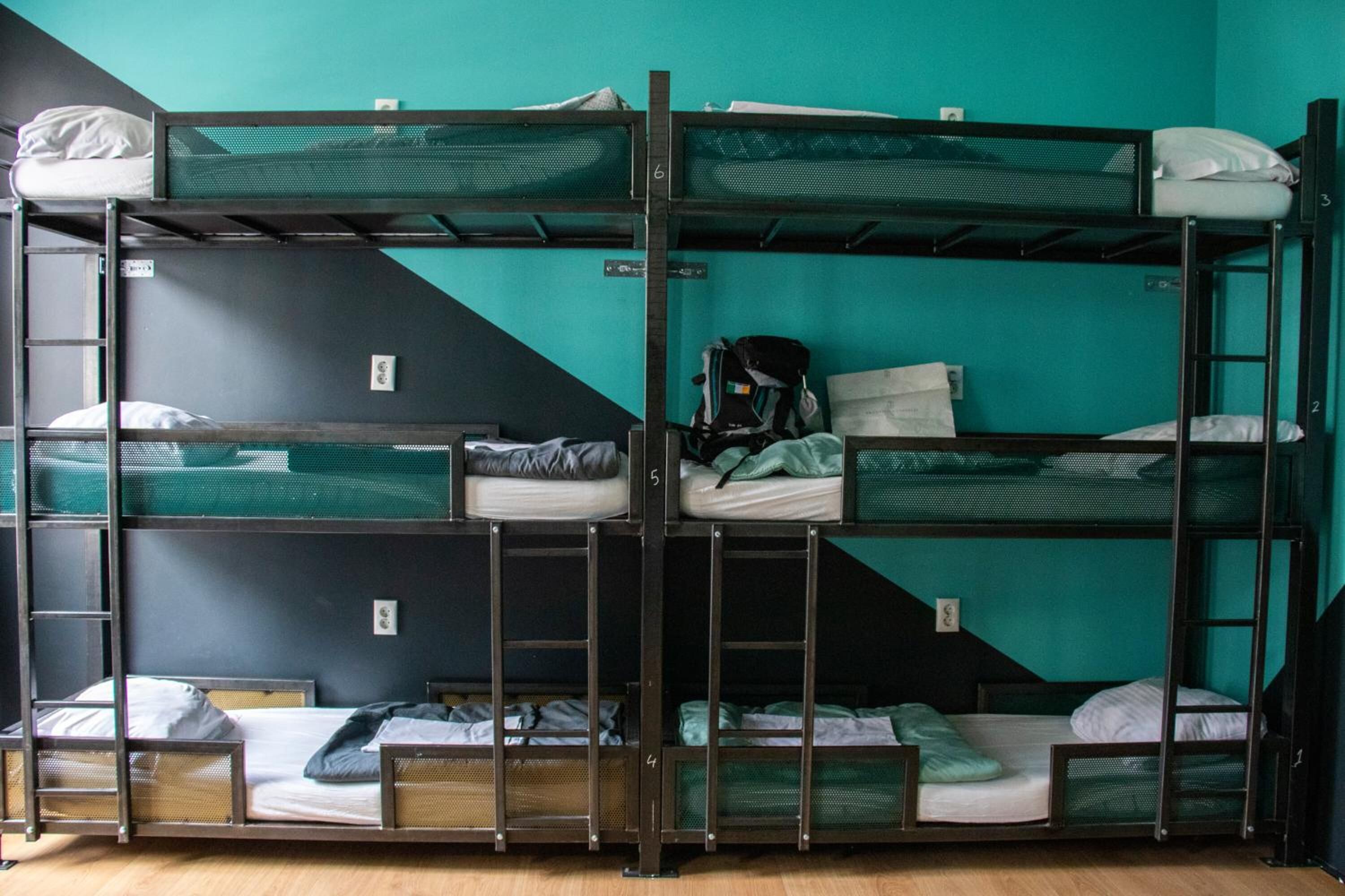 A bunk bed room with multiple beds, a ladder, and a backpack on one of the beds.
