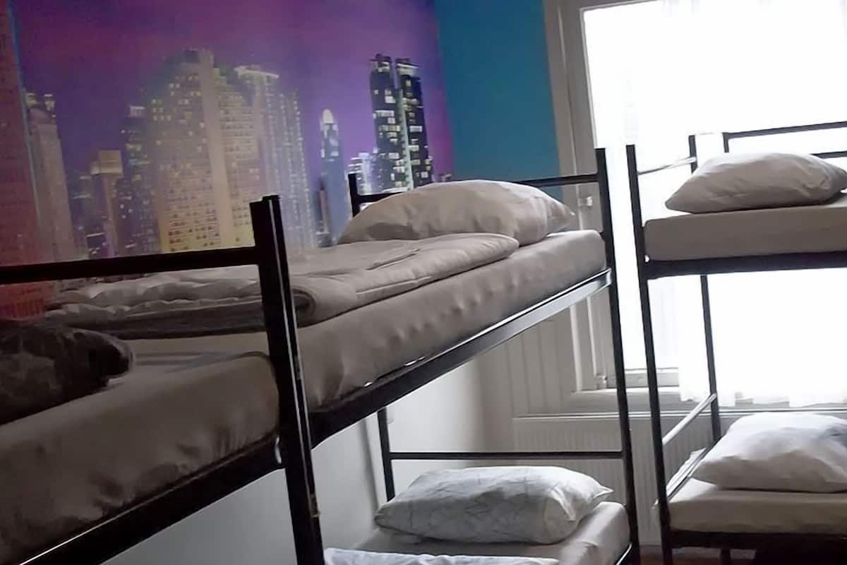 Ein Zimmer mit Etagenbetten, einer Stadtszenen-Mural und einem Fenster mit Vorhängen.