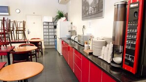 A kitchen with red cabinets, a coffee machine, and a refrigerator. - Marnix Hotel (Amsterdam)