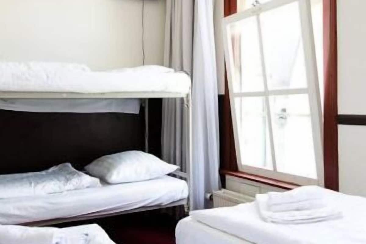 Una habitación de hotel con dos camas, un televisor montado en la pared y una ventana con cortinas.