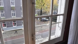 A view through a window with a street scene outside, including a parked car and a pedestrian. - Marnix Hotel (Amsterdam)