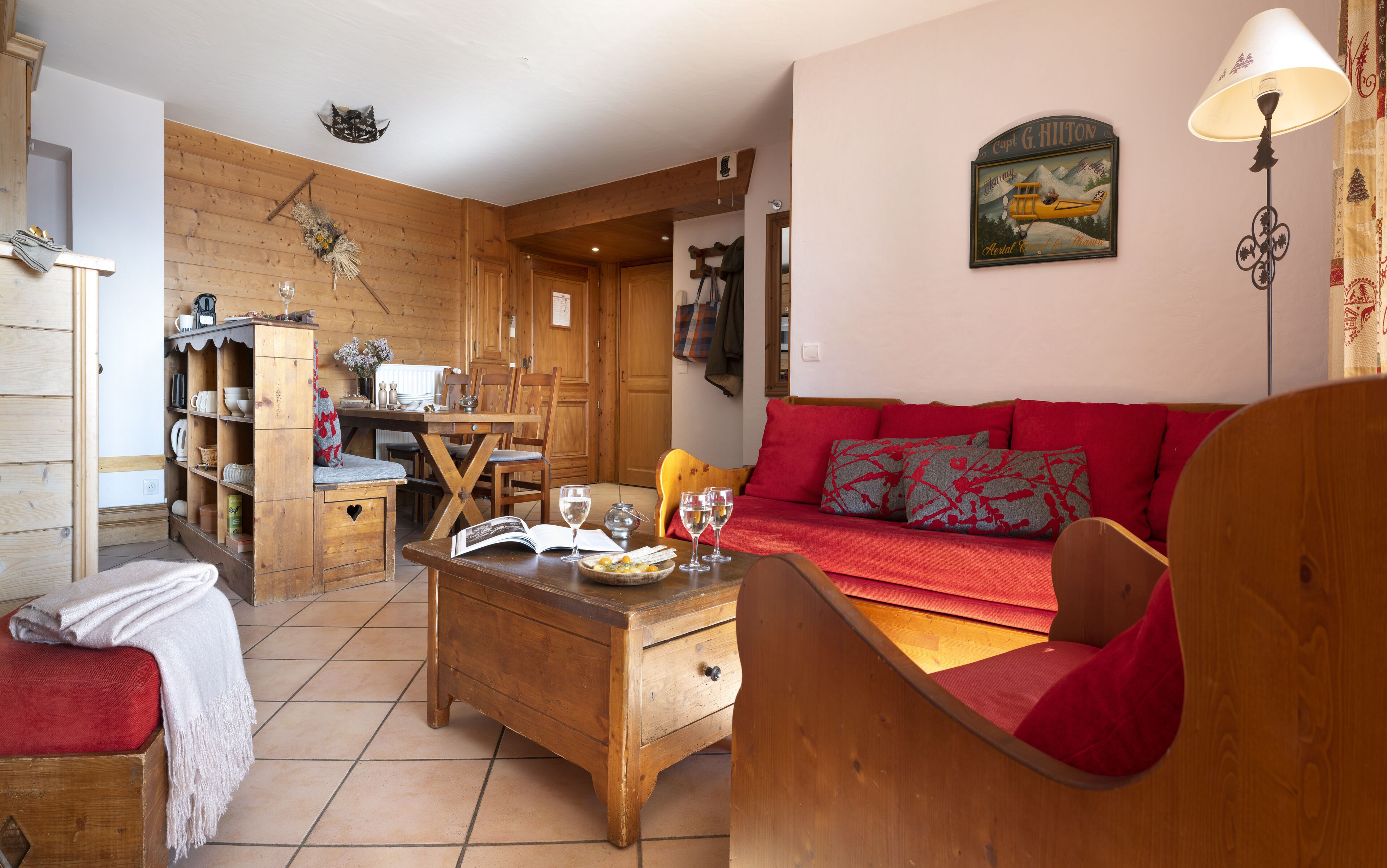 Ein gemütliches Holzinterieur mit einem roten Sofa, einem Holzesstisch und einem Bücherregal.