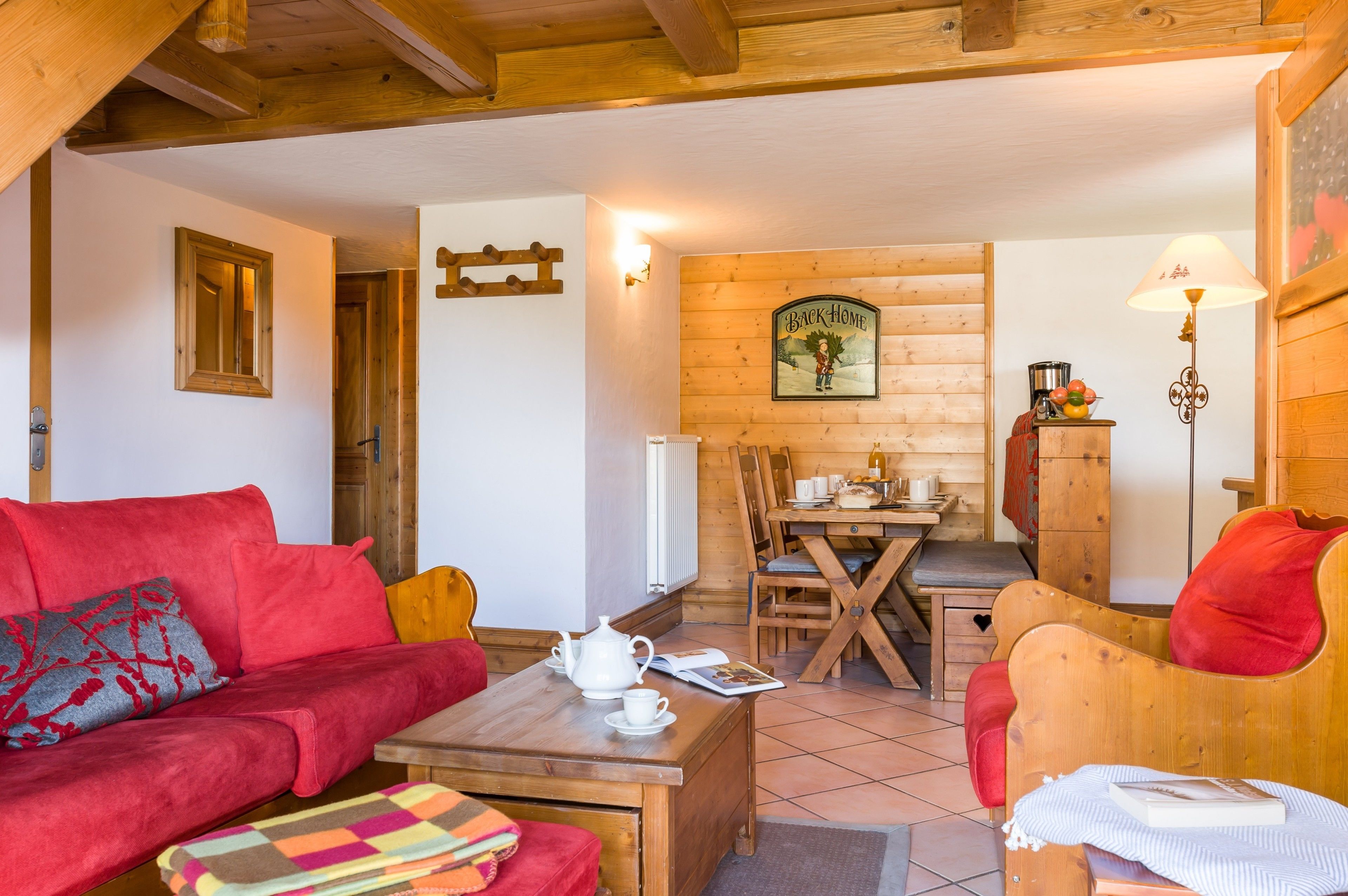 Una sala acogedora con un sofá rojo, una mesa de comedor de madera y una cocina al fondo.