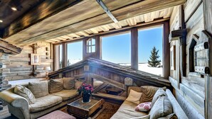 A log cabin interior with a cozy seating area, large windows, and a rustic wooden ceiling. - Résidence Pierre & Vacances Premium Les Alpages de Chantel (Bourg-Saint-Maurice)