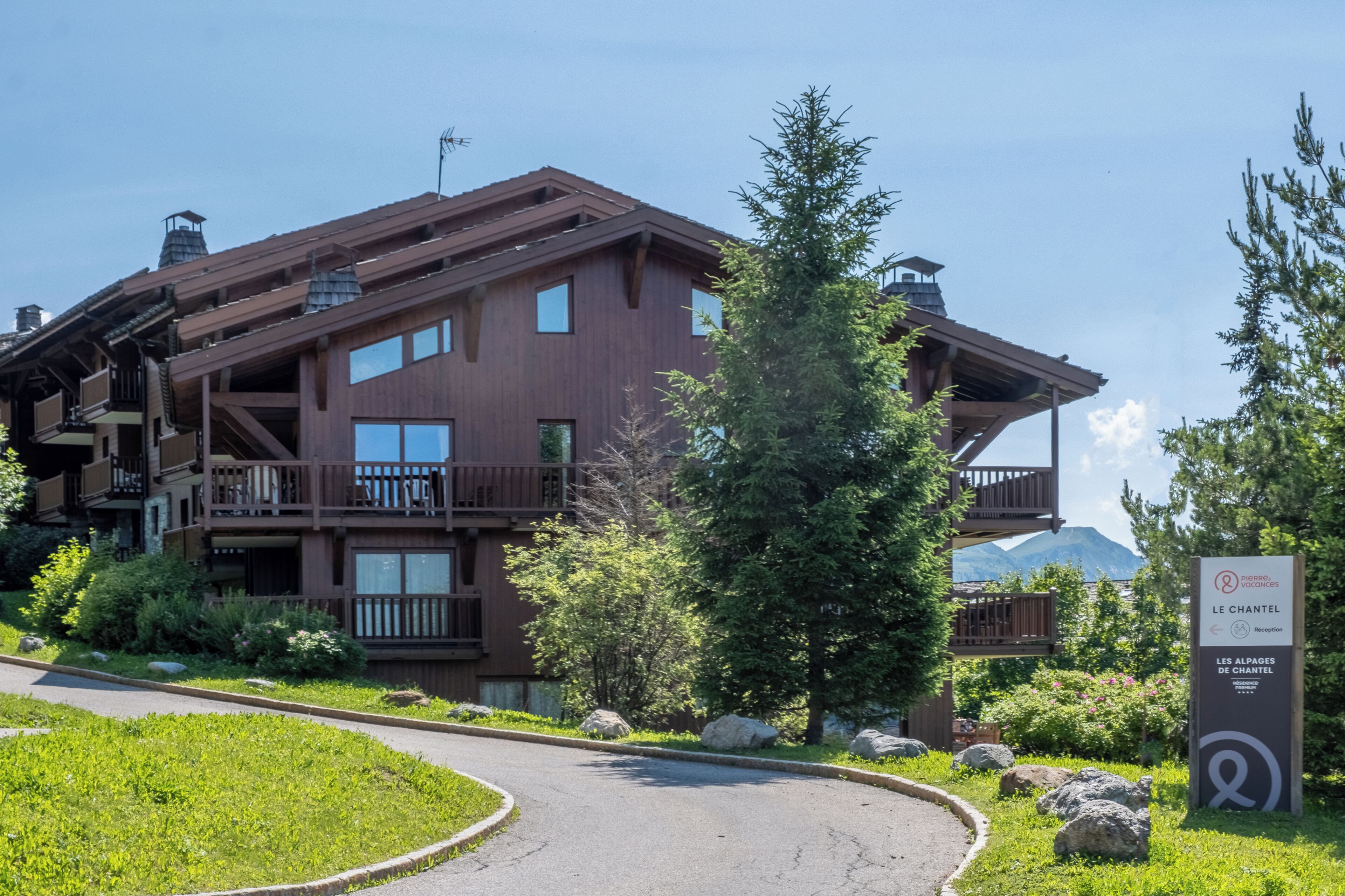 A multi-story lodge with balconies, a ski lift, and a sign indicating it's a ski resort.