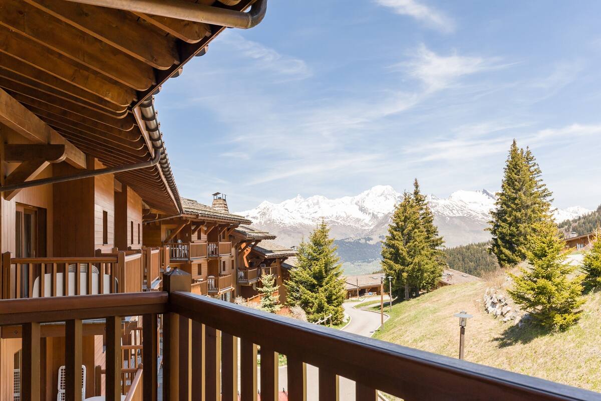 Un edificio de madera con un balcón que da a un paisaje nevado de montañas.