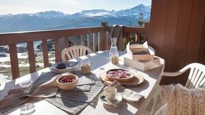 A table set for breakfast with a mountain view, including a pie, berries, and a coffee cup. - Résidence Pierre & Vacances Premium Les Alpages de Chantel (Bourg-Saint-Maurice)