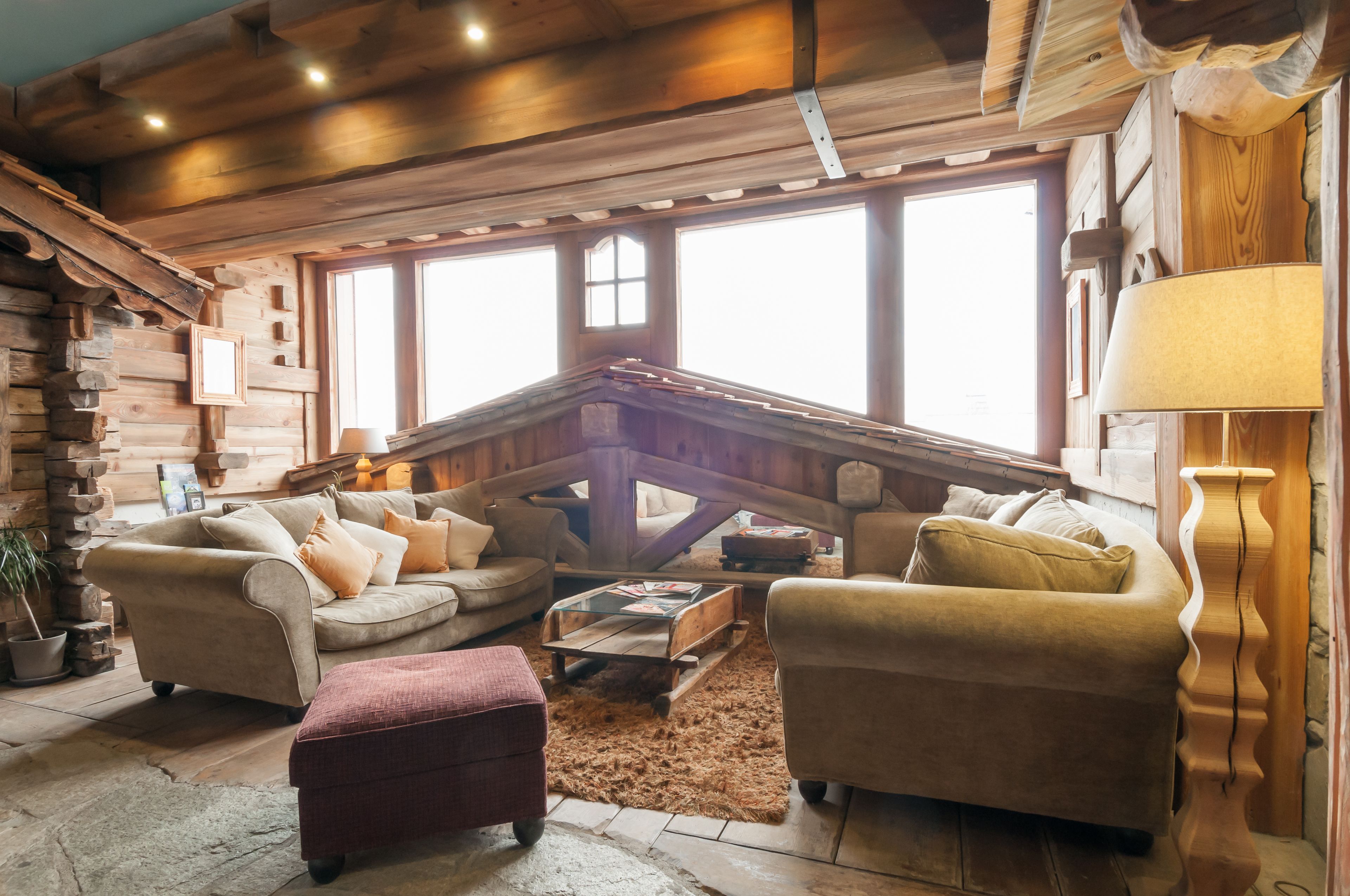 Ein gemütliches Blockhaus-Interieur mit Holzwänden, großen Fenstern und bequemen Sitzgelegenheiten.