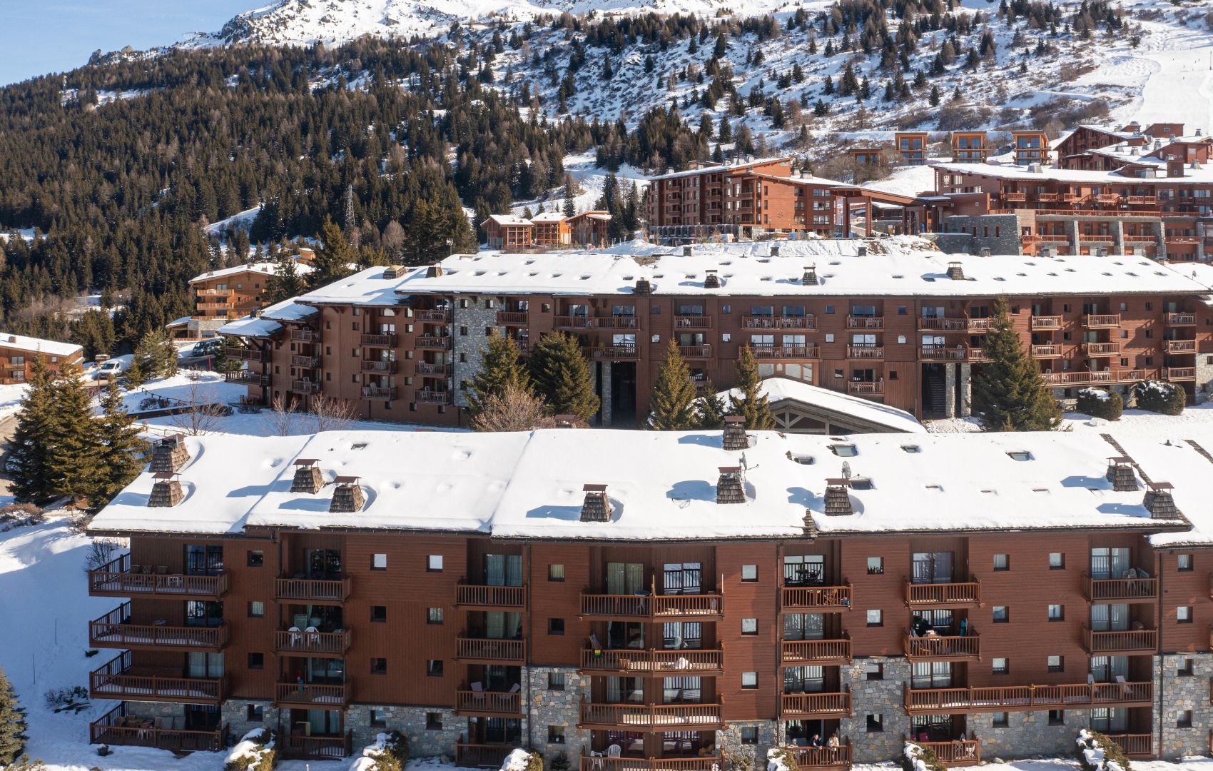 Ein mehrstöckiges Hotel mit Balkonen, eingebettet in eine verschneite Berglandschaft.