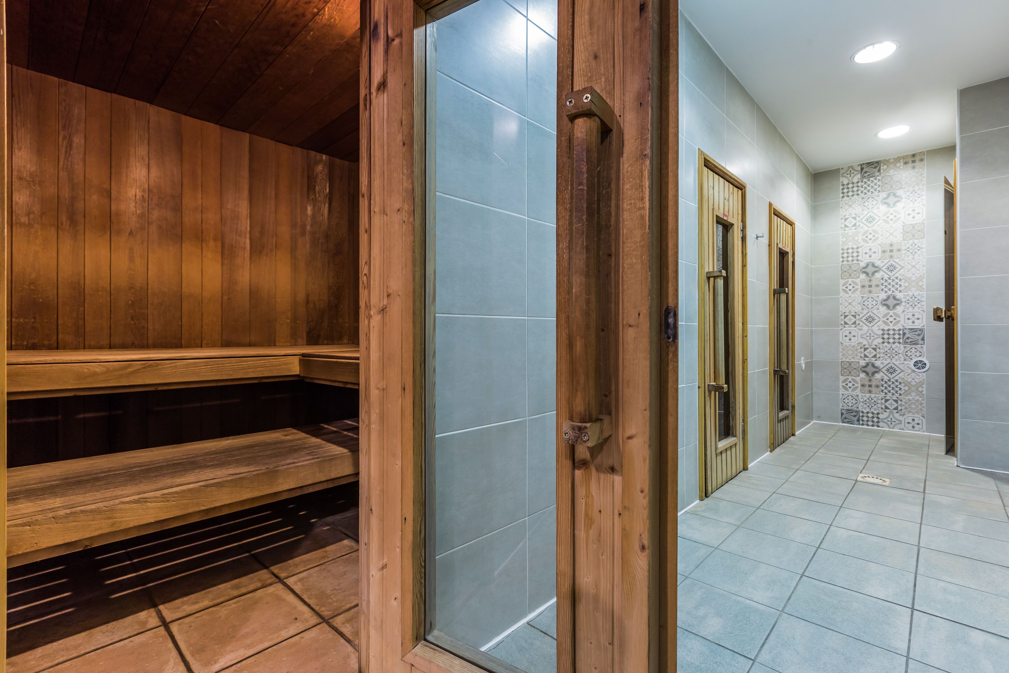 A wooden bench in a room with a tiled floor and a door leading to another room with patterned tiles.