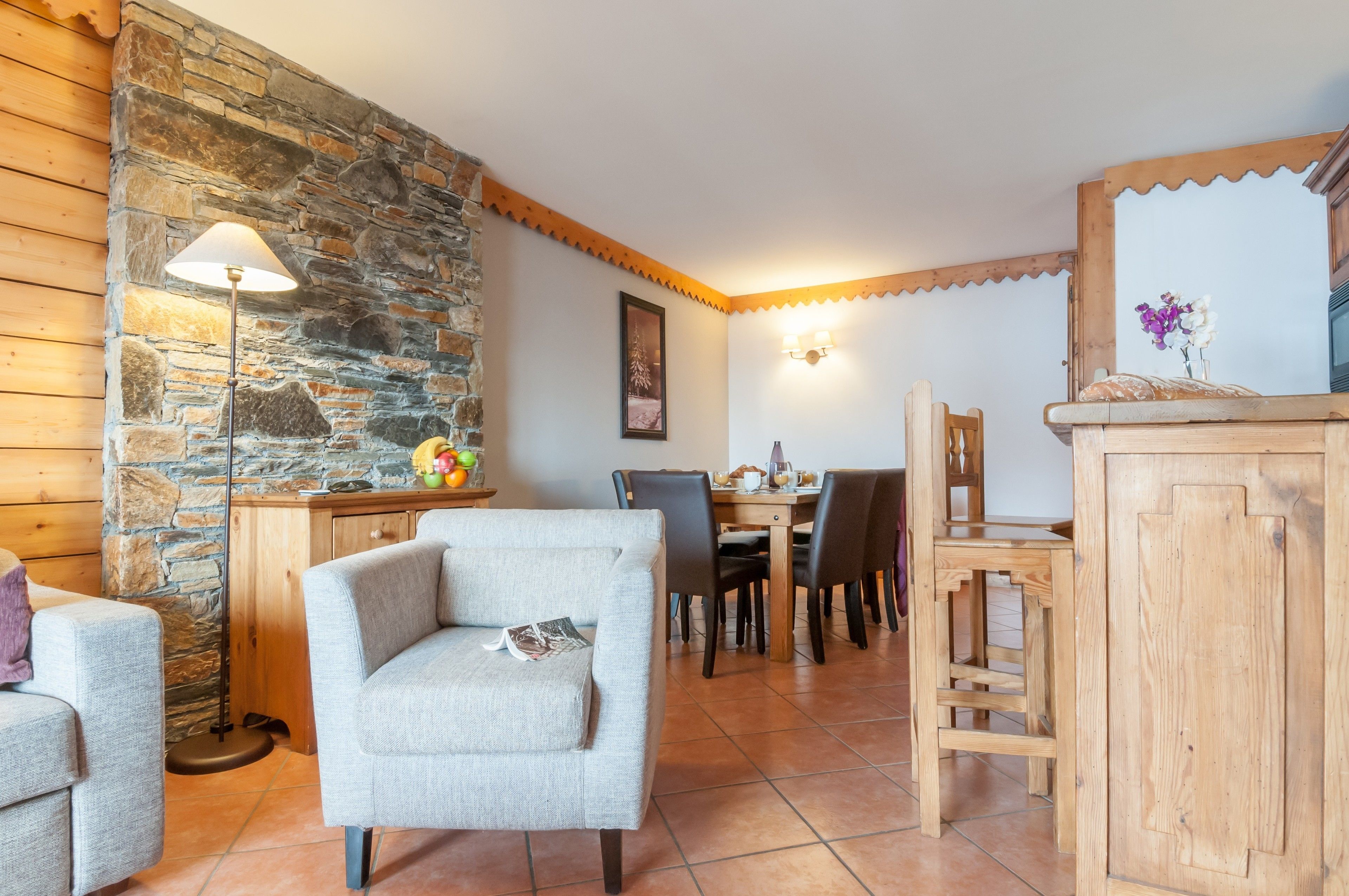 A cozy dining area with a stone wall, wooden furniture, and a lamp.