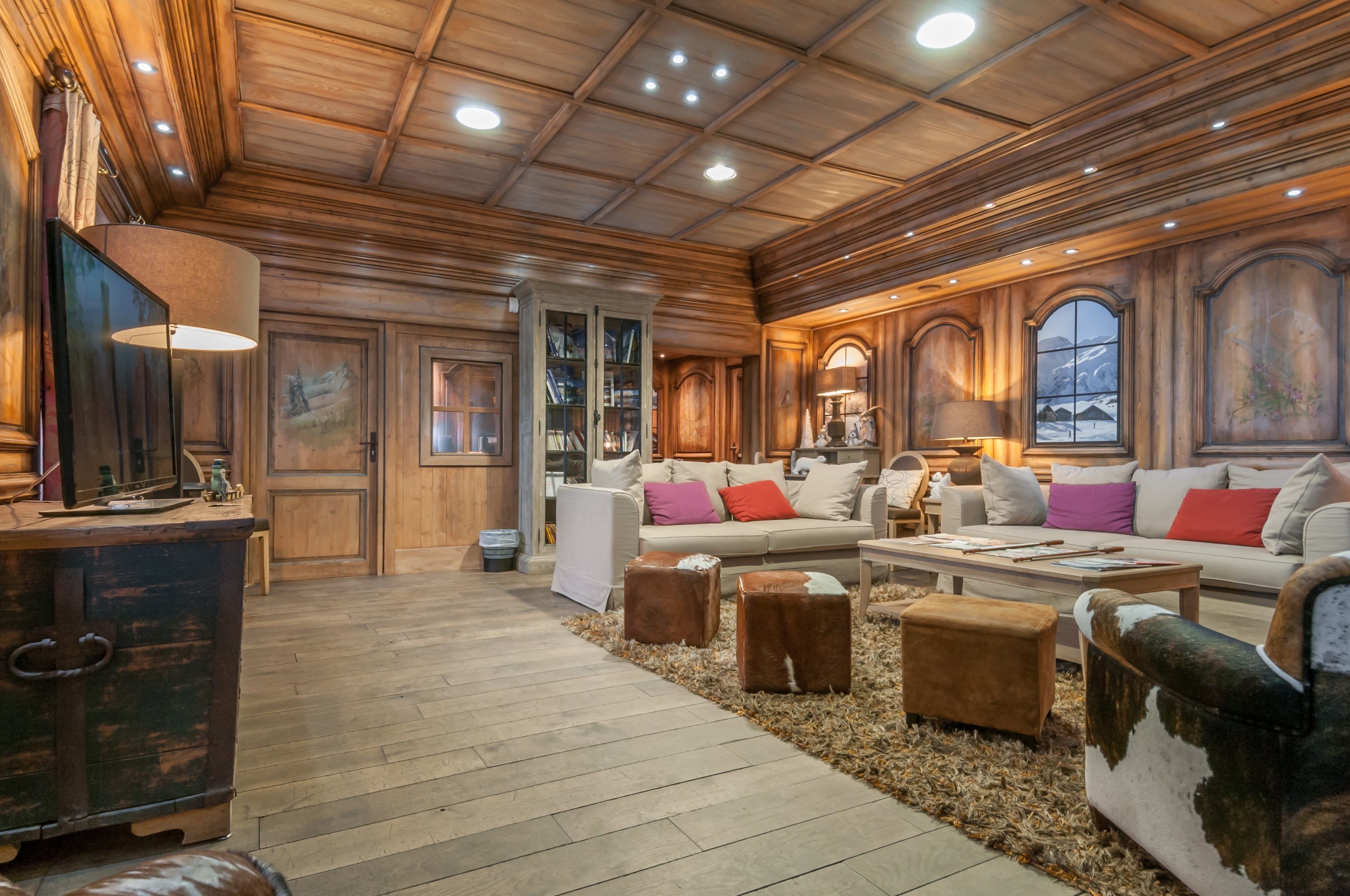 A spacious living room with a high wooden ceiling, a fireplace, and a large window with a mountain view.