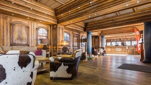 A spacious lobby with wooden paneling, a reception desk, and a large window. - Résidence Pierre & Vacances Premium Les Hauts Bois (Aime-la-Plagne)
