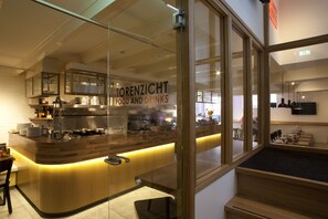 Un intérieur de restaurant moderne avec un comptoir, un espace cuisine et des places assises.