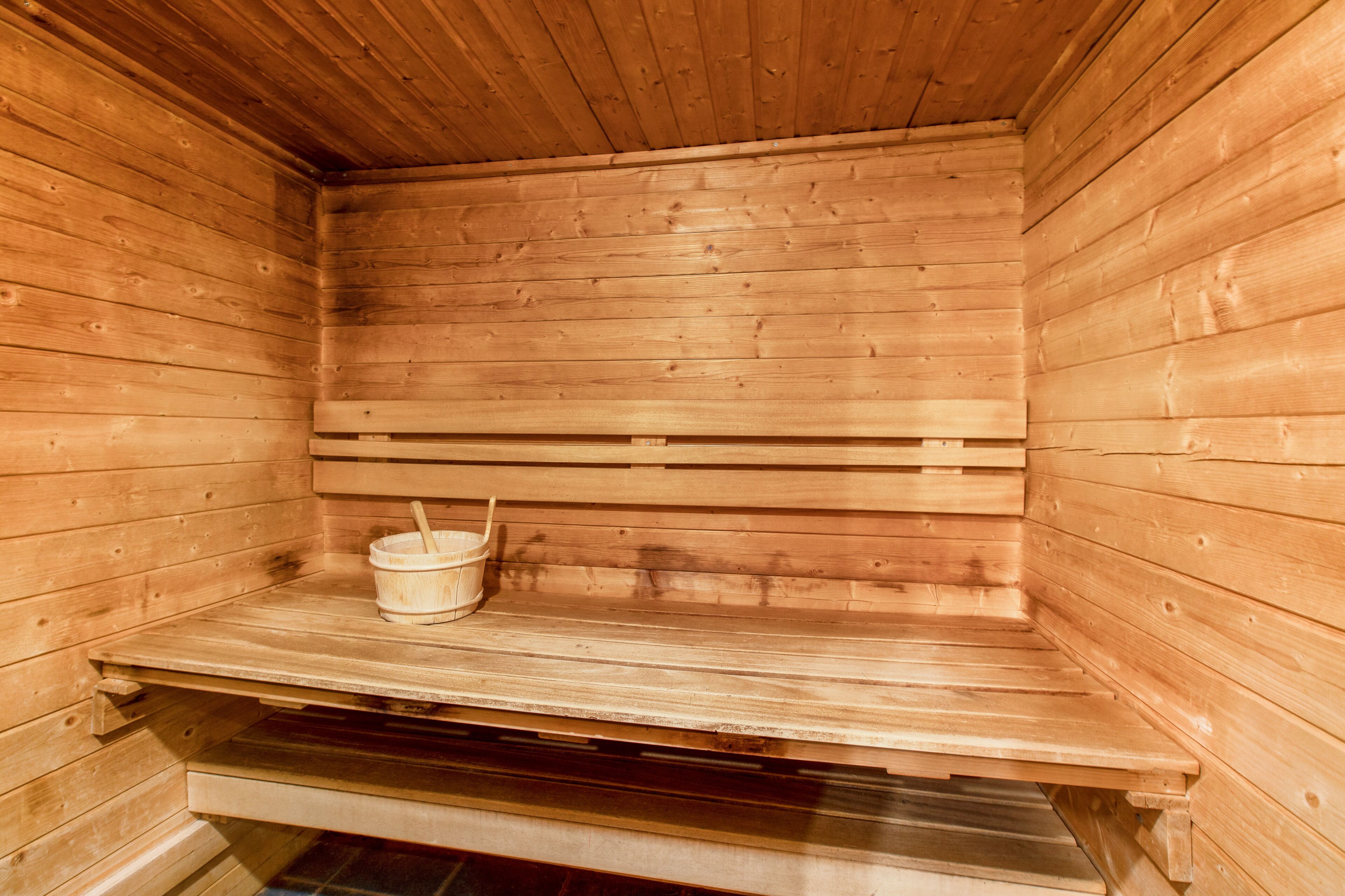 Un sauna en bois avec des bancs et un seau.