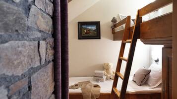 Cozy bedroom with a wooden bunk bed and ladder, a framed picture, and a child-friendly atmosphere.