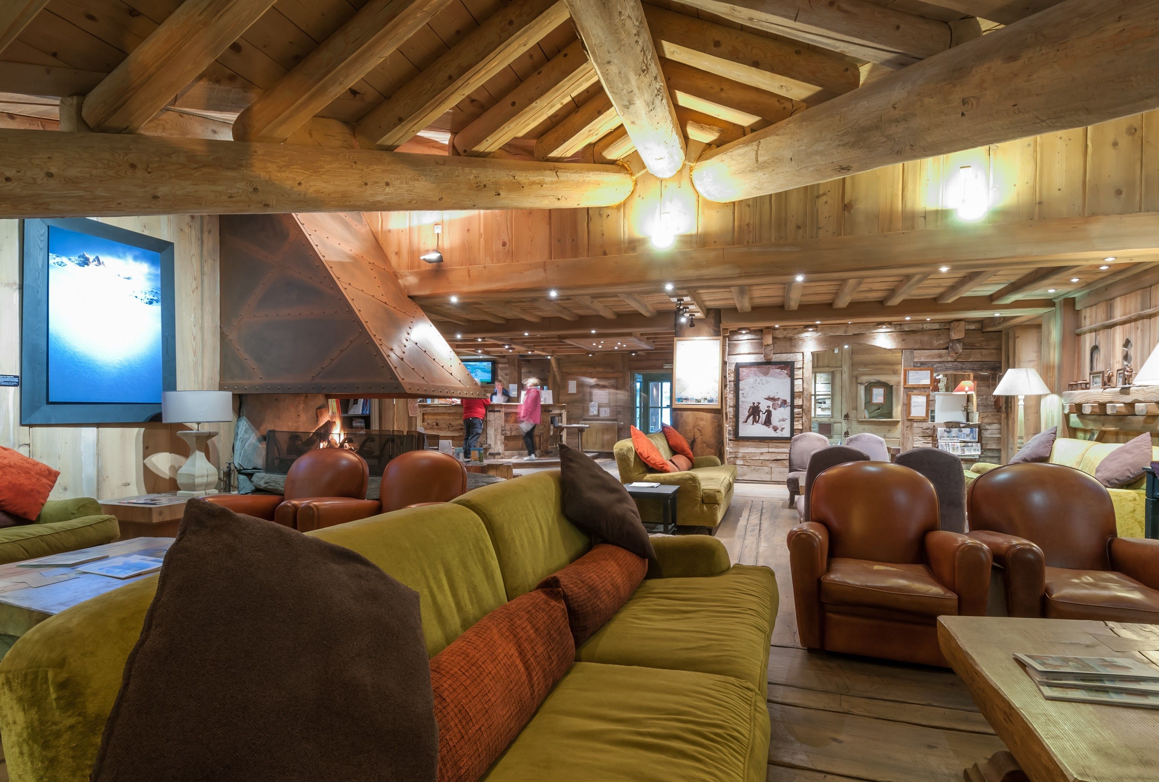 Un intérieur chaleureux avec des poutres en bois, une cheminée, des fauteuils en cuir et un canapé.